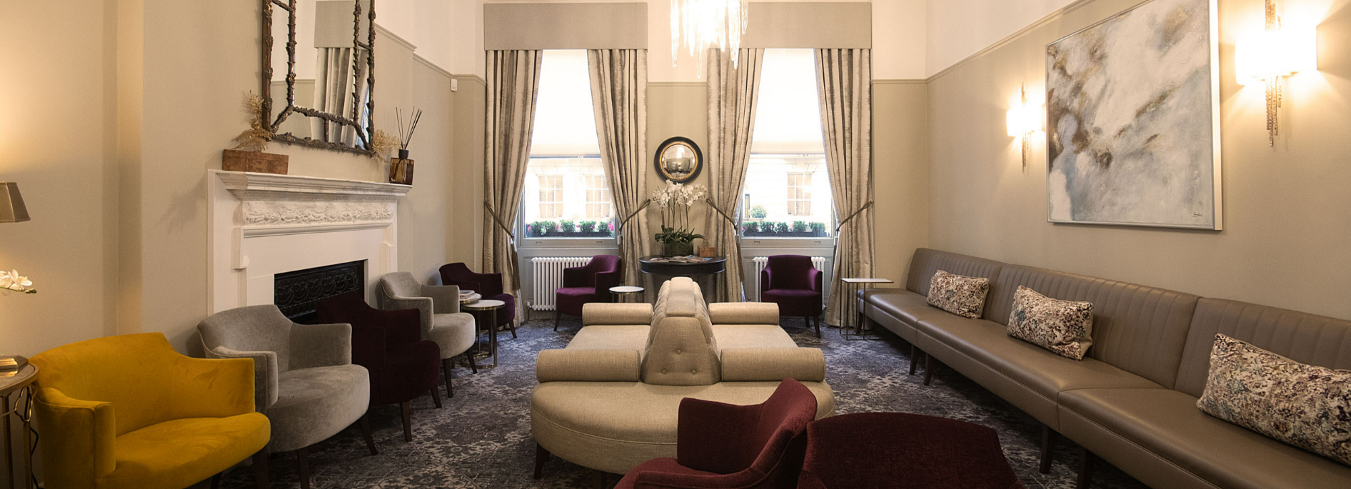 Patient lounge with marble fireplace, chandelier and banquette seating at 10 Harley Street